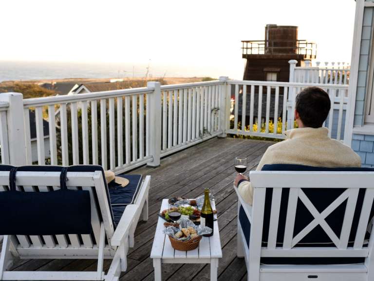 Ein Mann sitzt auf einem Deck mit einem Tisch und einer Flasche Wein