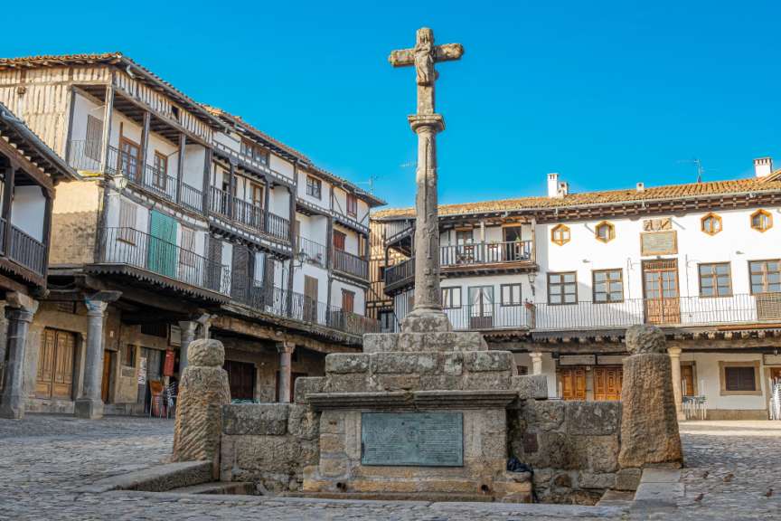 Eine Statue mit einem Kreuz darauf steht in einem Dorfplatz