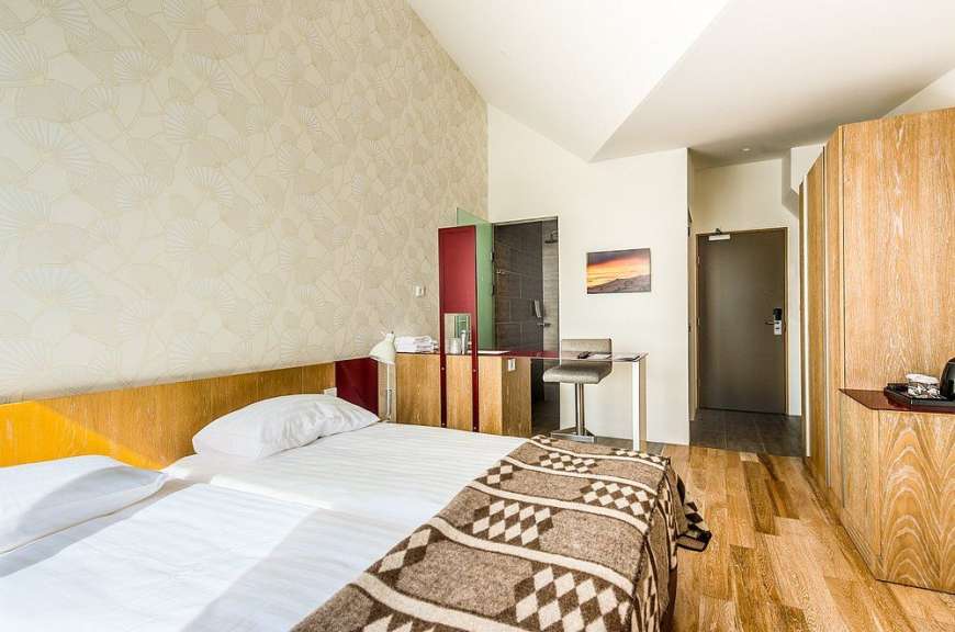 Ein Hotelzimmer mit zwei Betten, einem Schreibtisch und einer Tür zur Dusche.