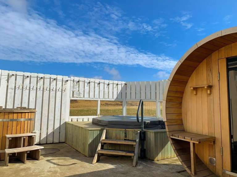 Ein Holzfass neben einem Whirlpool und einer Sauna