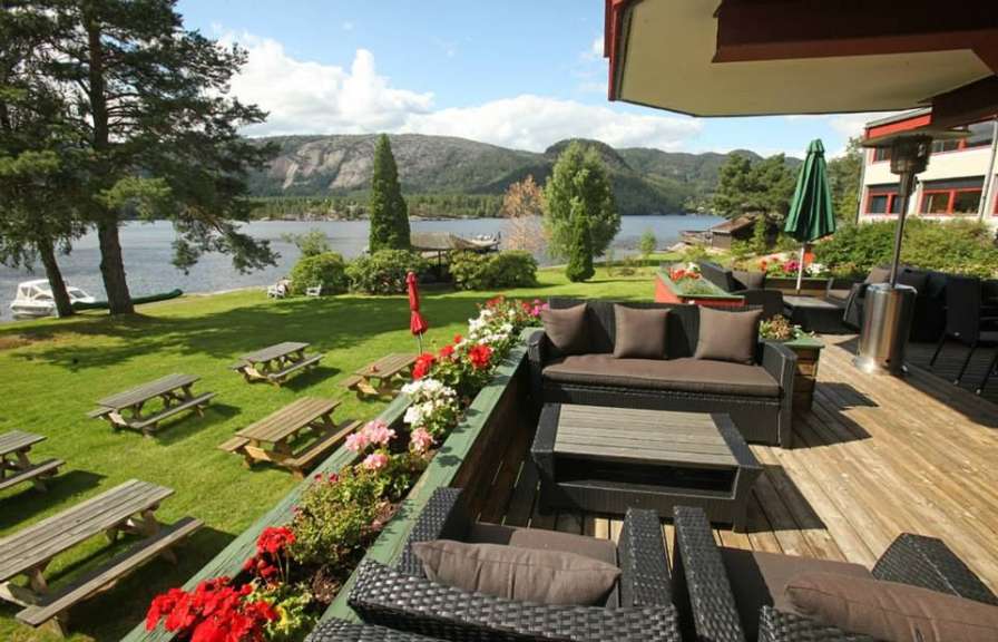 Eine Terrasse mit Möbeln und Picknicktischen mit Blick auf einen See