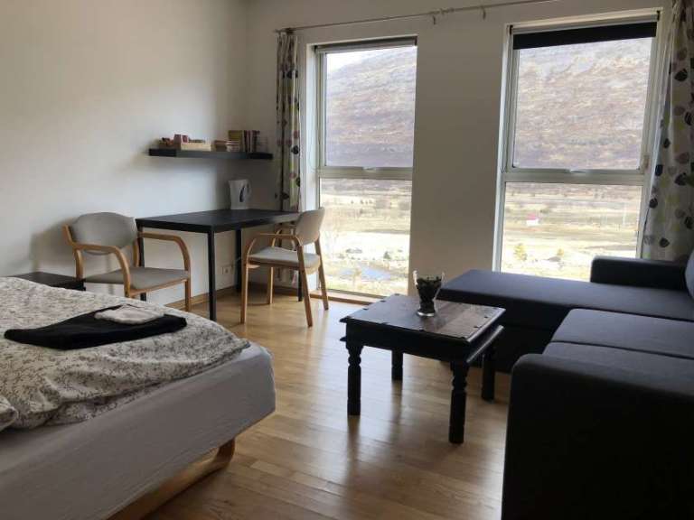 Ein Schlafzimmer mit einem Bett, einem Stuhl, einem Tisch und einem Fenster