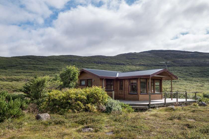 Ein kleines Holzhaus mit einer Veranda in der Mitte eines Feldes .