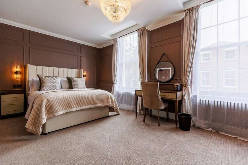 Ein luxuriöses Schlafzimmer mit einem großen Bett, einem Schreibtisch und einem Kronleuchter.
