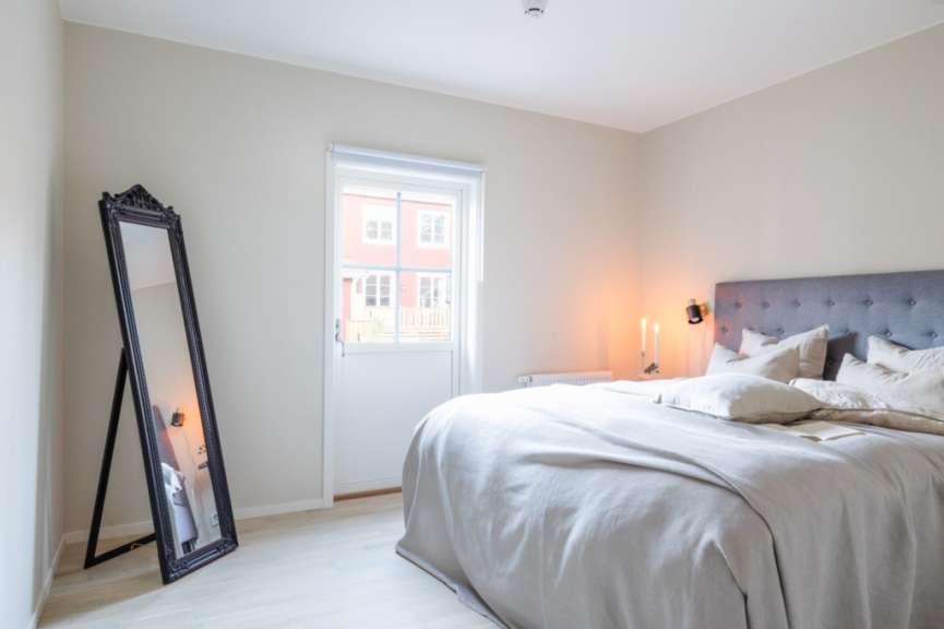 Ein Schlafzimmer mit einem Bett, einem Spiegel und einem Fenster mit Blick auf ein Haus.
