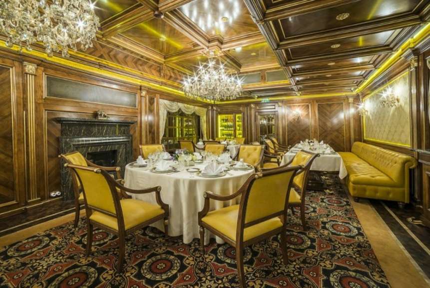 Ein luxuriöser Speisesaal ist mit Holzwänden, goldenen Akzenten und Kristalllüstern ausgestattet.