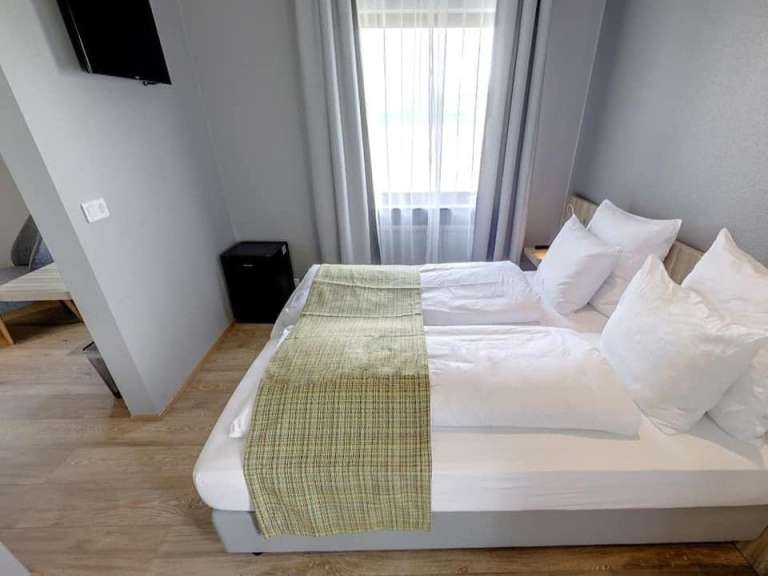 Eine saubere und ordentliche Hotelzimmer-Ecke mit Bett und Fernseher an der Wand.