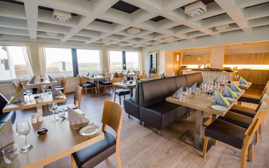 Dies ist ein Bild von einem Restaurant mit vielen Tischen, die mit Stoffservietten und Gläsern für Gäste eingedeckt sind.