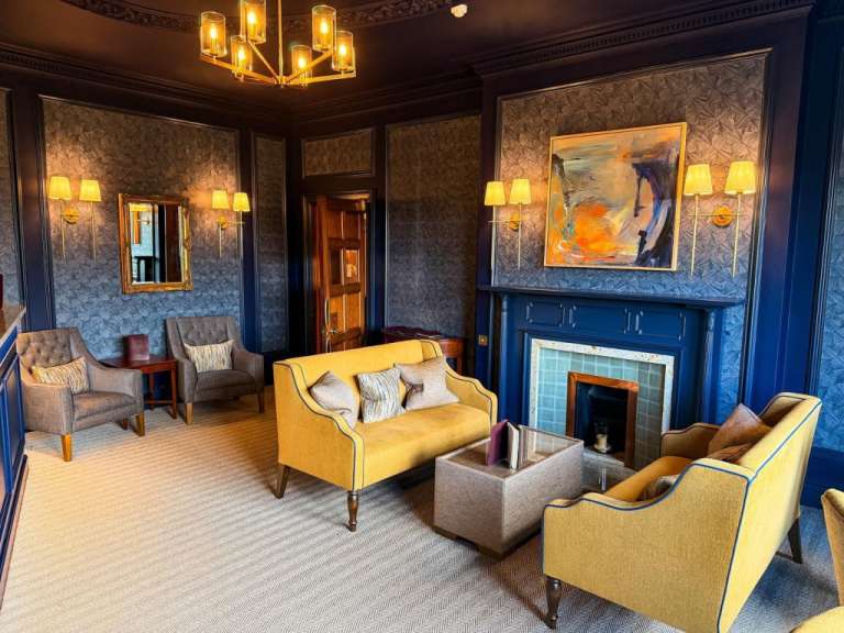 Ein stilvolles Wohnzimmer mit blauen Wänden, einem Kamin und gelben Möbeln.
