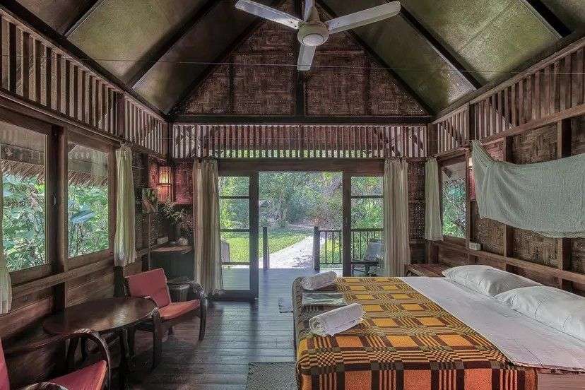 Ein rustikales Schlafzimmer mit einem Himmelbett, Sitzbereich und Blick auf eine grüne Landschaft.