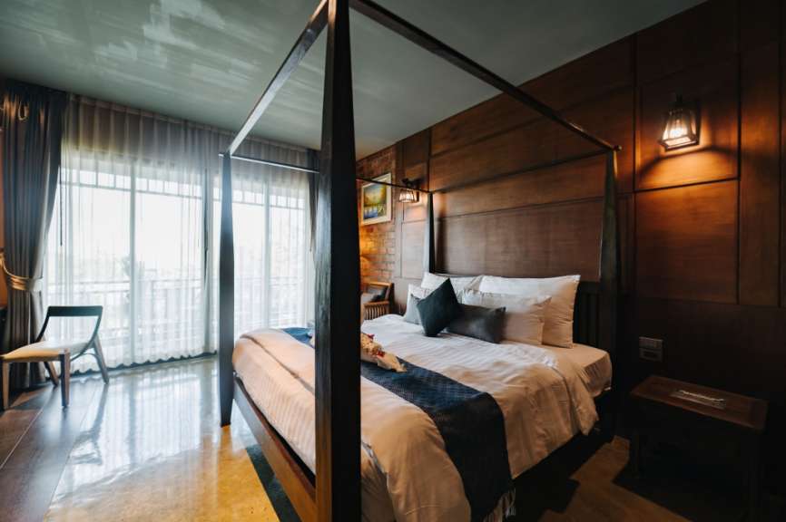 Ein luxuriöses Schlafzimmer mit einem Himmelbett, das von Holzwänden und einem großen Fenster mit Vorhängen umgeben ist.