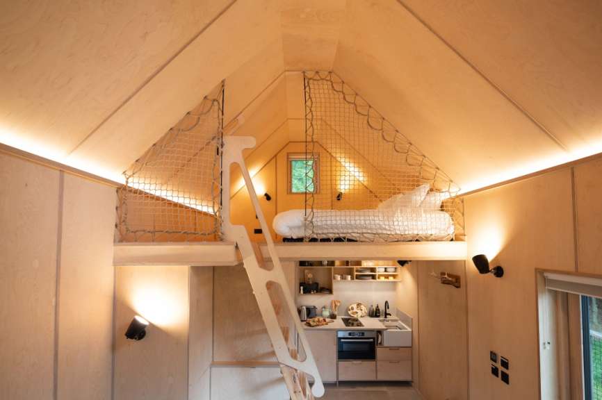 Holzgetäfeltes Interieur mit Hochbett, Netzabsperrung und kleiner Küche.