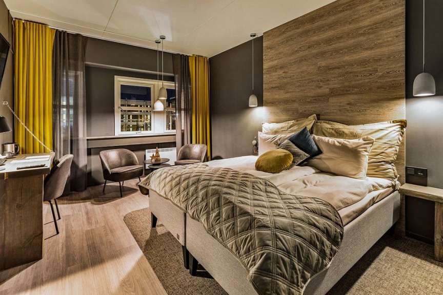Ein Hotelzimmer mit einem Bett, zwei Sesseln, einem Schreibtisch und einem Fenster.
