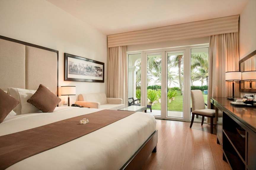 Ein luxuriöses Hotelzimmer mit Blick auf den Strand und Palmen.