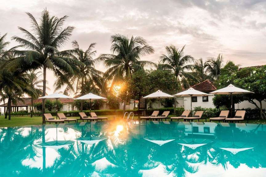 Ein Swimmingpool und Liegestühle sind im goldenen Licht des Sonnenuntergangs zu sehen.