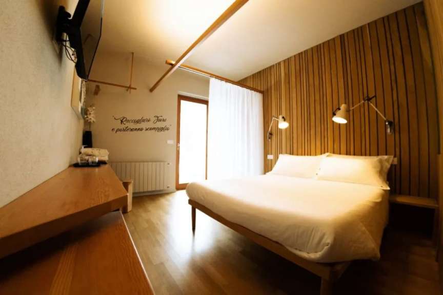 Ein minimalistisch eingerichtetes Schlafzimmer mit Holzwandverkleidung, einem Bett und einem Fernsehgerät.