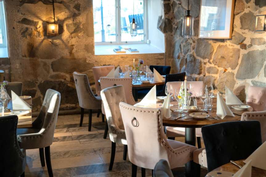 Das Bild zeigt einen schön gedeckten Tisch in einem rustikalen Restaurant mit Steinwänden.