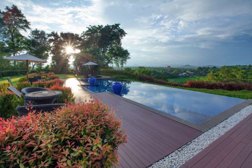 Ein Infinity-Pool mit Blick auf eine grüne Landschaft bei Sonnenuntergang.