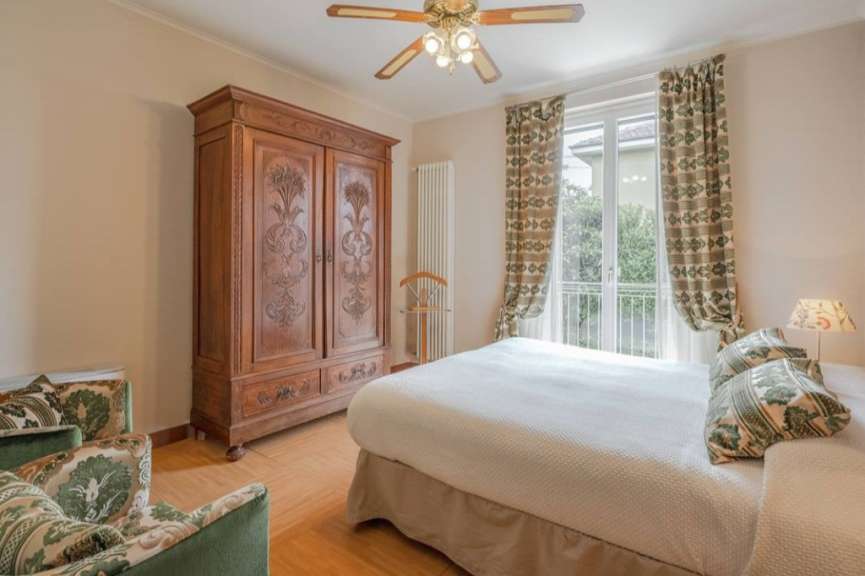 Ein geräumiges Schlafzimmer mit einem großen Kleiderschrank, einem Doppelbett, zwei Sesseln und einem Deckenventilator.