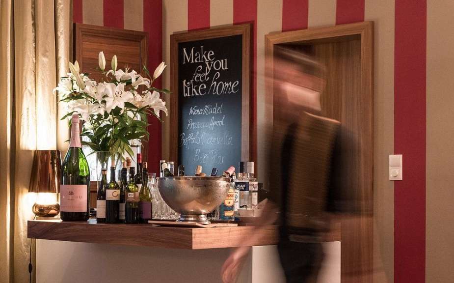 Ein Mann verschwimmt vor einer Theke mit Blumen, Getränken und einer Tafel mit einer Speisekarte.