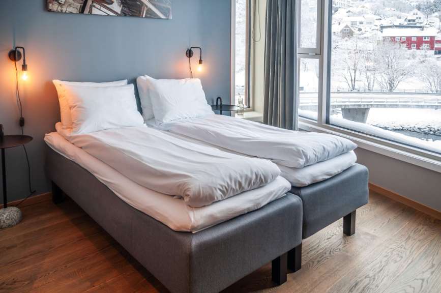 Ein stilvolles Schlafzimmer mit zwei Betten und Blick auf eine verschneite Landschaft.