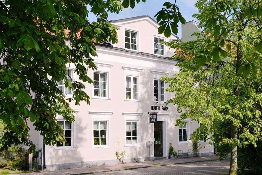 Ein helles Gebäude, wahrscheinlich ein Hotel, wird von üppigen grünen Bäumen umrahmt.