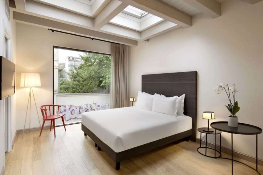 Ein modern eingerichtetes Schlafzimmer mit großem Fenster und einem Bett.