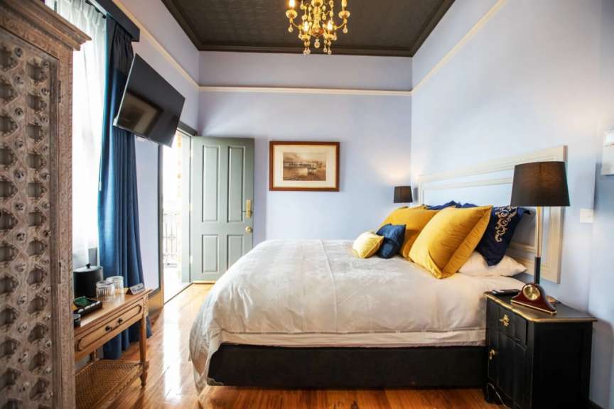 Ein helles Schlafzimmer mit einem großen Bett, dekorativen Kissen und einem eleganten Kleiderschrank.