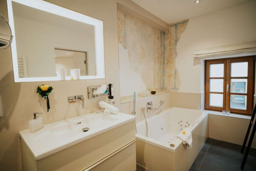 Ein elegantes Badezimmer mit Waschbecken, Badewanne und einem Fenster im Alpenstil.