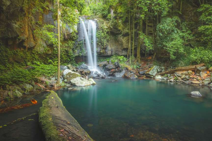 Ein wunderschöner Wasserfall fließt in einen türkisfarbenen Pool inmitten einer üppigen, grünen Dschungellandschaft.