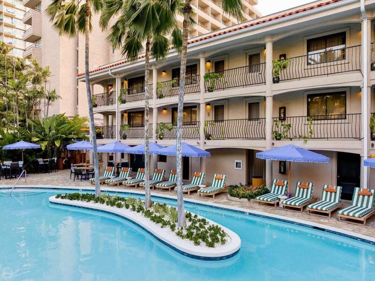 Ein Resort mit einem Schwimmbecken, Liegestühlen und Palmen.