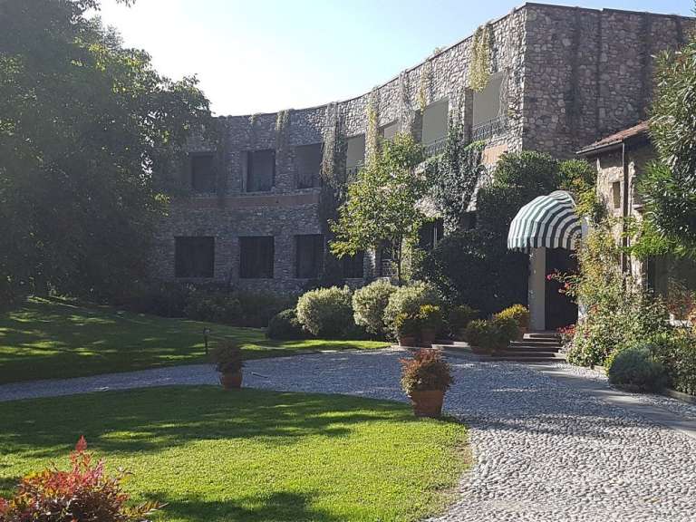 Ein Gebäude aus Stein mit einem begrünten Innenhof und einer gepflasterten Auffahrt.