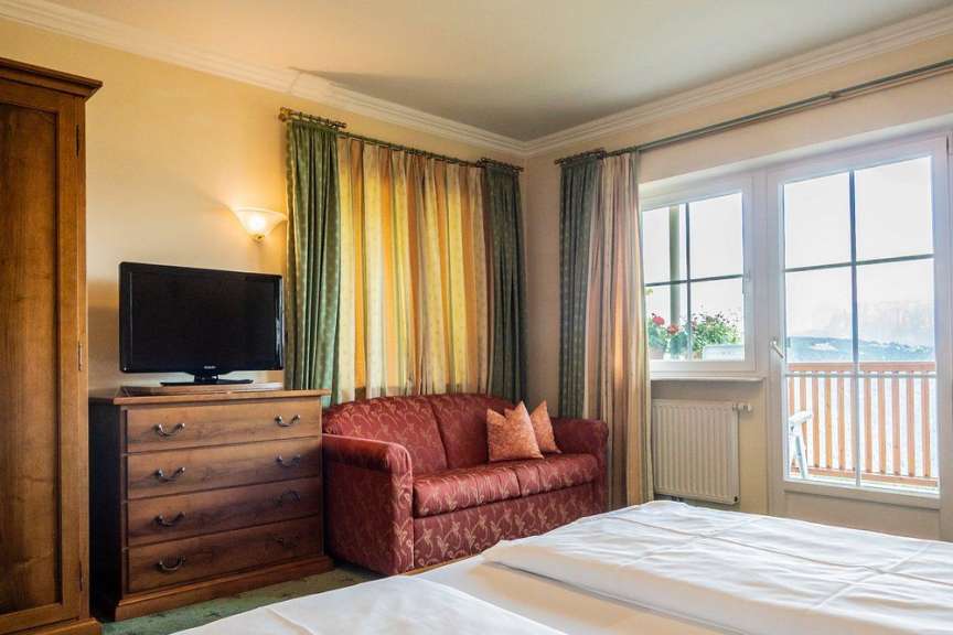 Dieses Bild zeigt ein Schlafzimmer mit einem Bett, einem Sofa, einem Fernseher und einem Kleiderschrank.
