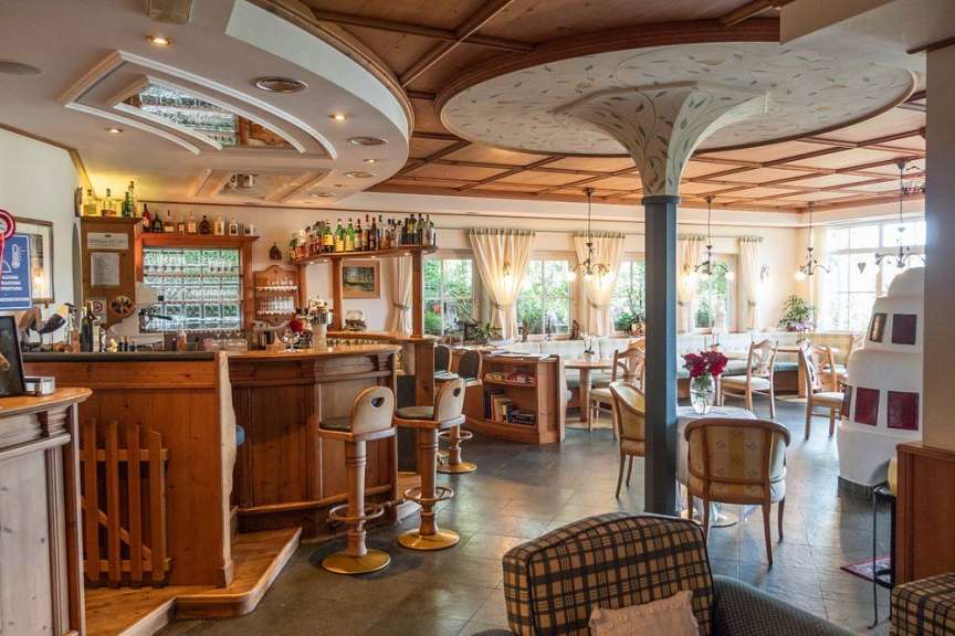 In einem gemütlichen Restaurant mit Holztäfelung an Decke und Bar sind Bartische, Stühle und ein Kamin zu sehen.