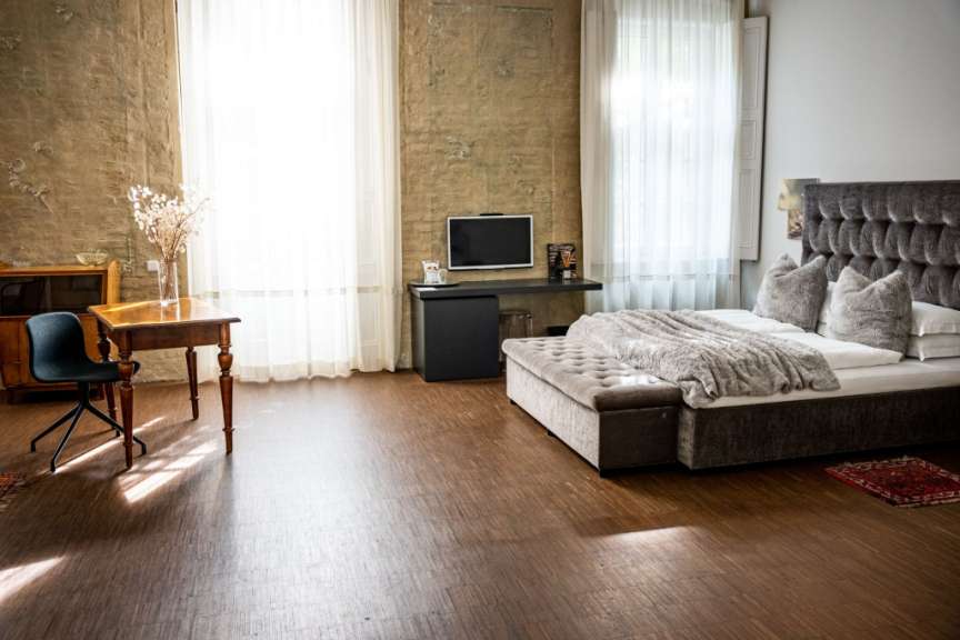 Ein Schlafzimmer mit einem Bett, einem Schreibtisch und einem Tisch in einem Raum mit Holzböden und großen Fenstern.