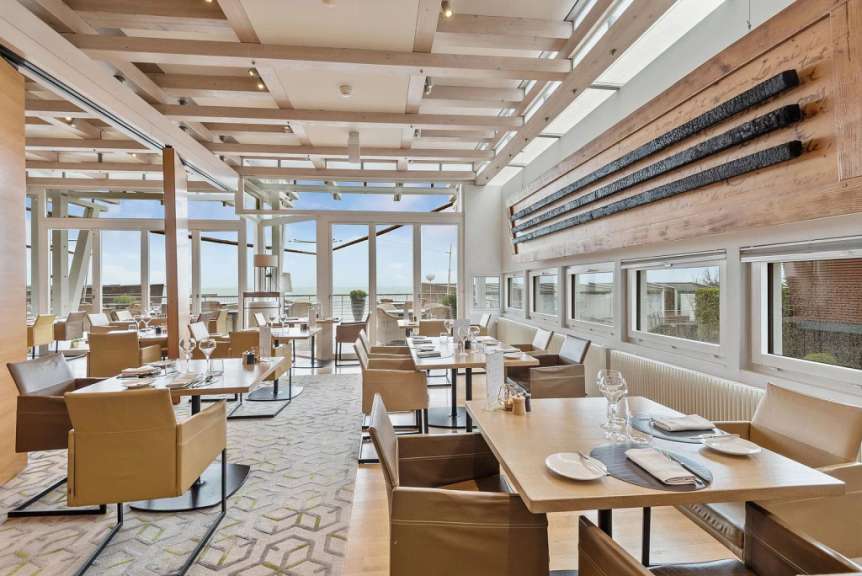 Ein geschmackvoll eingerichtetes Restaurant mit Blick aufs Meer und einer modernen Holzdecke.