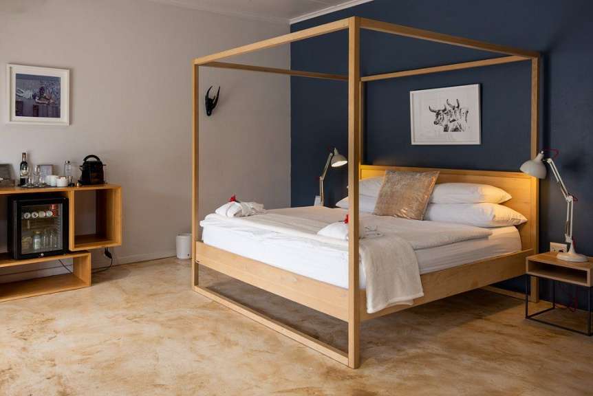 Ein Hotelzimmer mit einem Himmelbett, einem Nachttisch mit Lampe und einem Schrank mit Minibar.