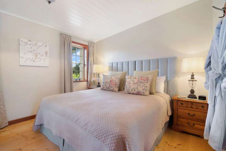 Ein gemütliches Schlafzimmer mit einem großen Bett, zwei Nachttischen und einem blauen Bademantel, der an der Wand hängt.