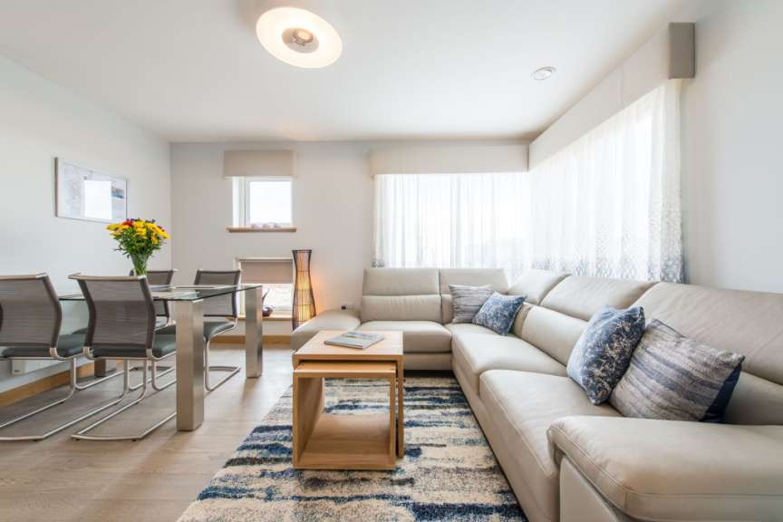 Ein helles Wohnzimmer mit einem Esstisch, einer Couch und einem Teppich.