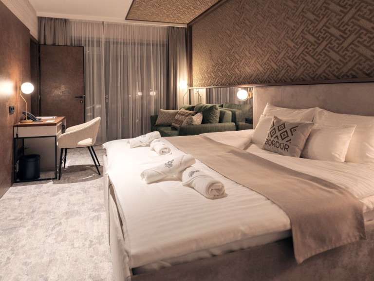 Ein luxuriöses Hotelzimmer mit einem bequemen Bett, einem Schreibtisch und einem Sofa.