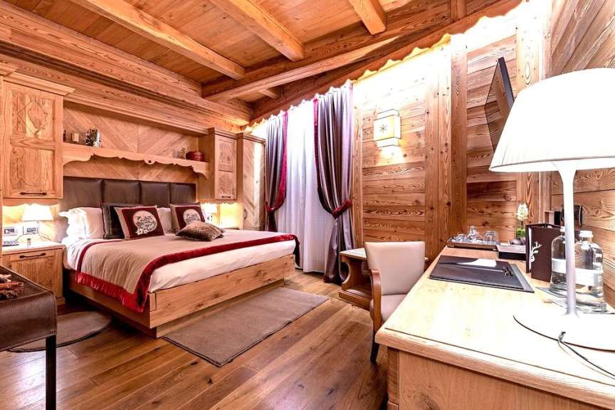 Ein luxuriöses Hotelzimmer ist mit Holzwänden und -decken, einem großen Bett und einem Schreibtisch ausgestattet.
