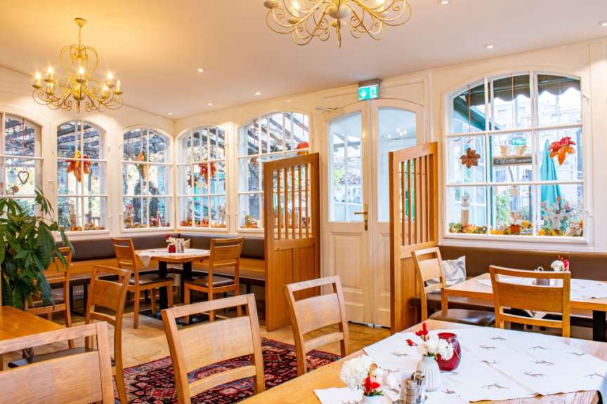 Ein Restaurant mit Holztischen und -stühlen, reichlich dekoriert mit Herbstmotiven, beleuchtet von einer eleganten Deckenleuchte.