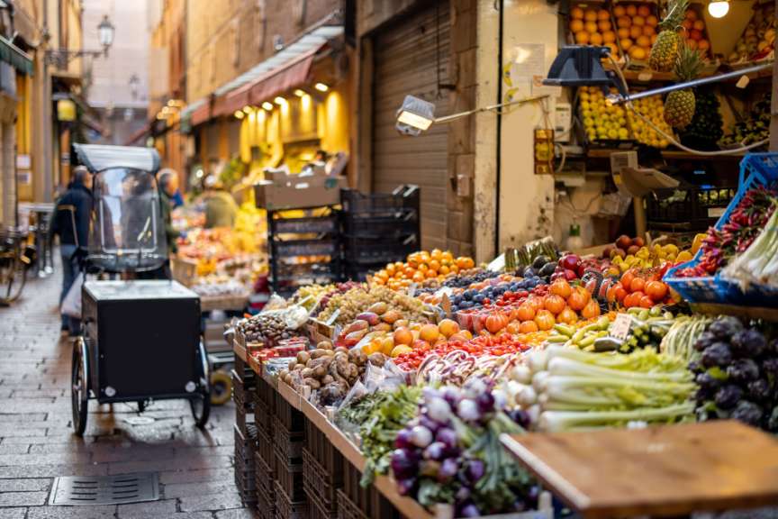 Ein Marktstand mit frischem Obst und Gemüse in einer Gasse.