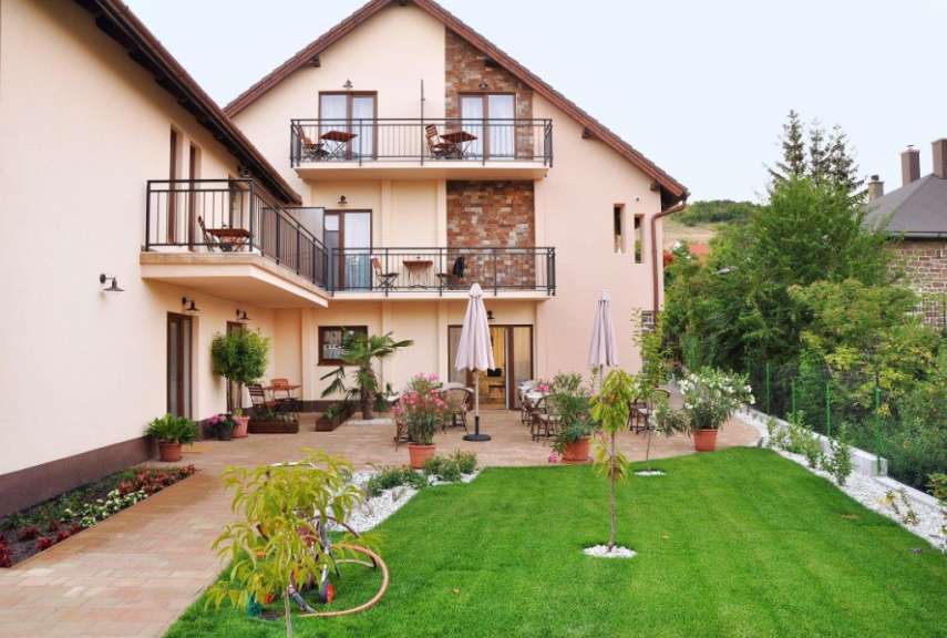 Eine helle Fassade eines Hauses mit Balkonen und einem gepflegten Garten.