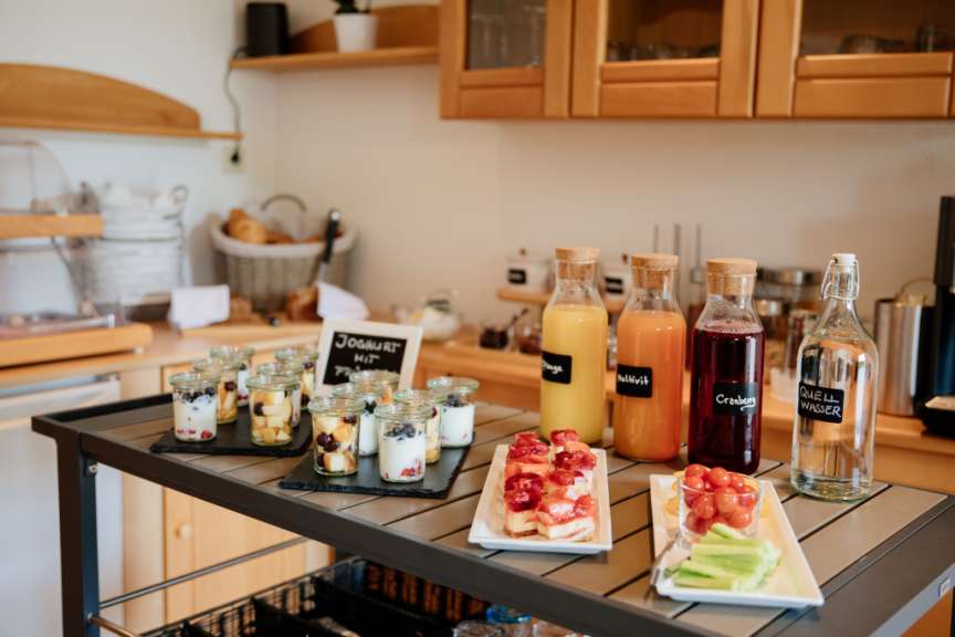 Ein Buffet mit verschiedenen Lebensmitteln wie Joghurt mit Früchten, Kuchen, Obst und Getränken.