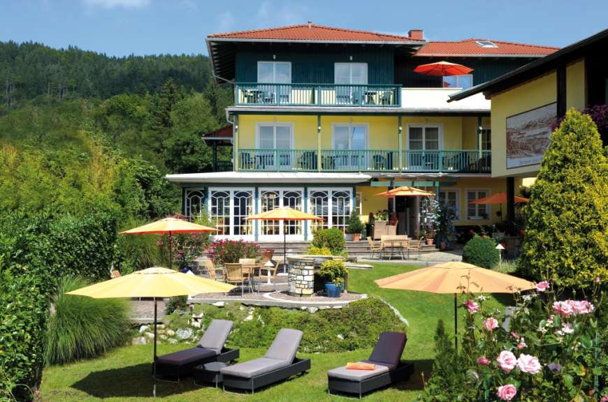 Auf diesem Bild ist ein Hotel mit einem grünen Garten und einem blauen Himmel zu sehen.