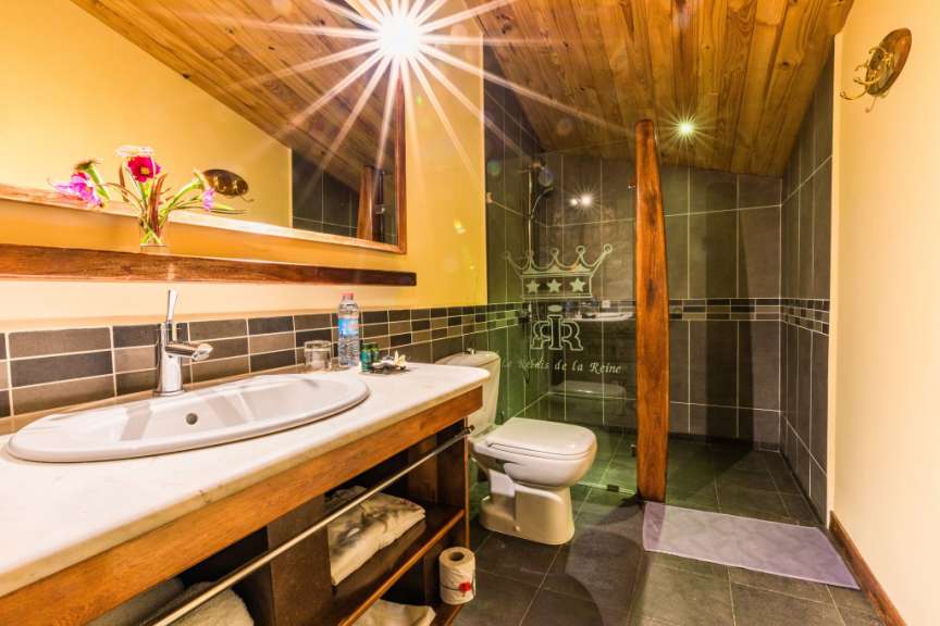 Ein Badezimmer mit Waschbecken, Toilette und Duschkabine, beleuchtet von einem hellen Sonnenlichteffekt an der Decke.