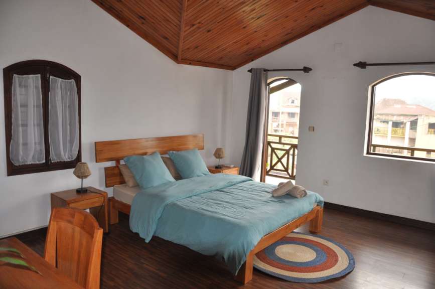 Ein Schlafzimmer mit einem Holzbett, weißen Bettwäsche und blauen Kissen, zwei Nachttischen mit Lampen und einem runden Teppich.