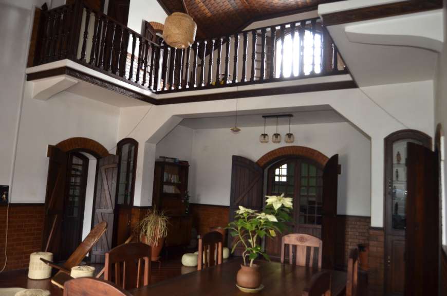 Das Bild zeigt das Innere eines großen Raumes mit einem Holzbalkon im Obergeschoss und einer breiten Treppe, die in den unteren Bereich führt.