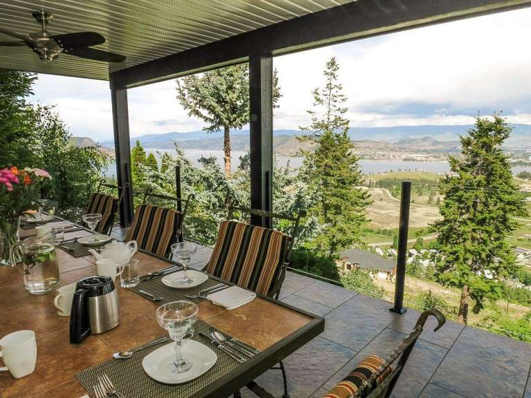 Eine gedeckte Tafel auf einer Veranda mit Blick auf eine Stadt und einen See.